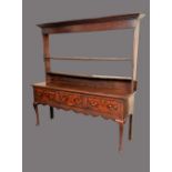 A George I oak dresser, open two shelf plate rack, the base fitted with three cockbeaded drawers,