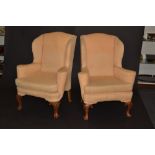 A pair of George II style walnut wingback arm chairs, loose squab seats, upholstered in yellow,