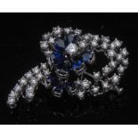 A diamond and sapphire ribbon knot brooch, the white metal wire work frame,