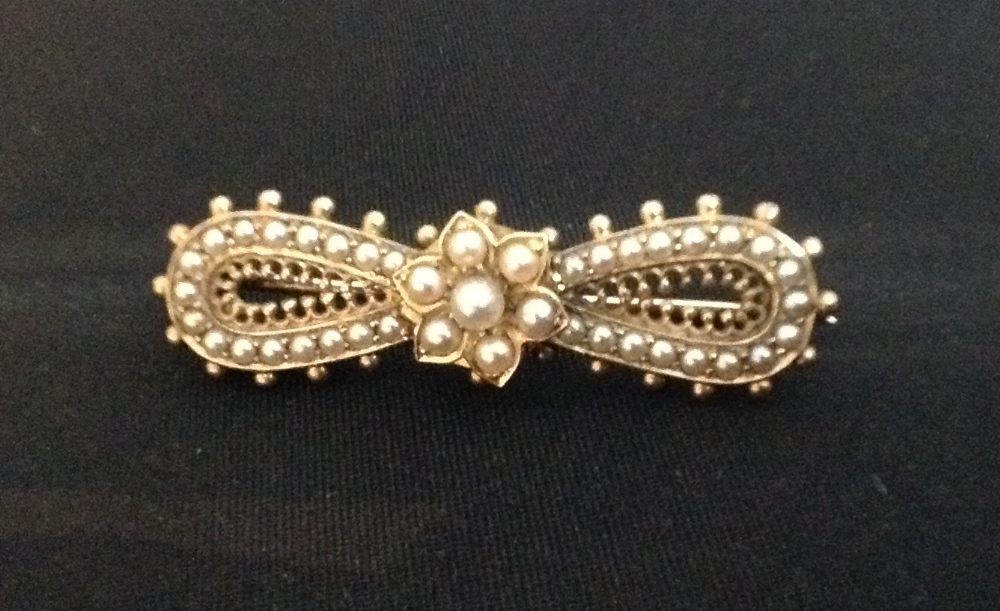 A Victorian seed pearl and ribbon bow brooch, central flower head set with seven seed pearls,