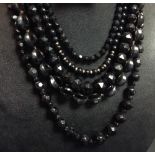 A black glass jet effect bead necklace, rounded quarter lobed beads, barrel clasp;  another,
