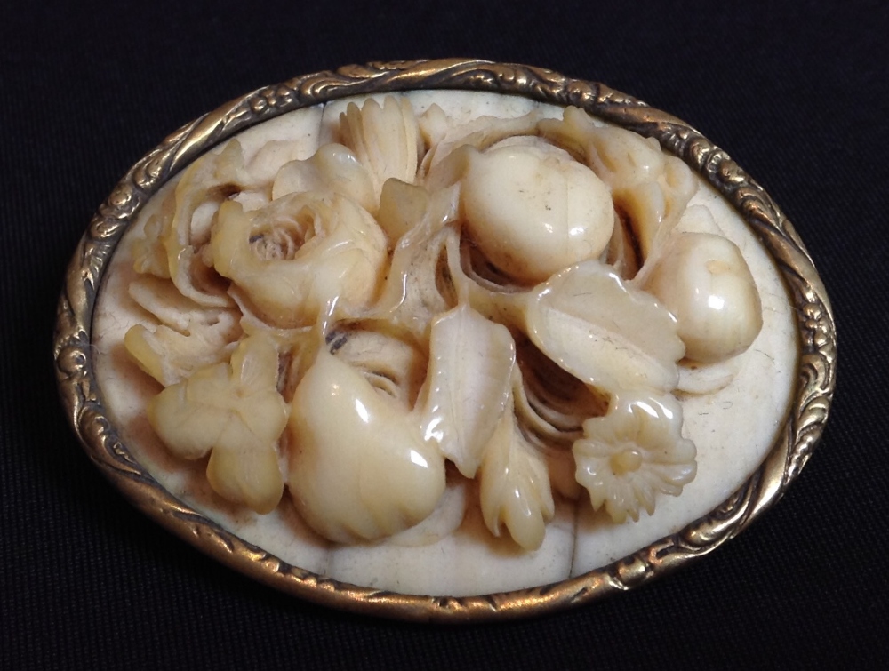 A 19th century Dieppe ivory brooch, the carved oval panel a floral study,