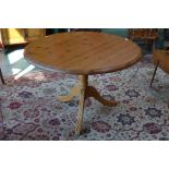 A contemporary pine pedestal breakfast table, circular top, turned column,