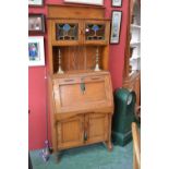 An Arts and Crafts oak bureau cabinet, galleried top, two stained glass door cabinet over recess,