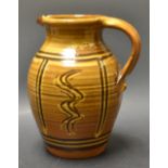 A Studio pottery slip glazed terracotta jug, decorated with panels of slip dragged waves,