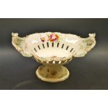 A continental porcelain pedestal oval dish, ornate flowering swag handles, painted floral swags,