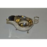 A George V silver sauceboat, wavy rim, flying loop handle, pad feet, 15.