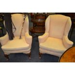 A pair of George II style walnut wingback arm chairs, loose squab seats, upholstered in yellow,