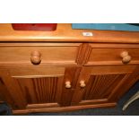 A low pine side cabinet, fitted with two drawers and two cupboard doors,