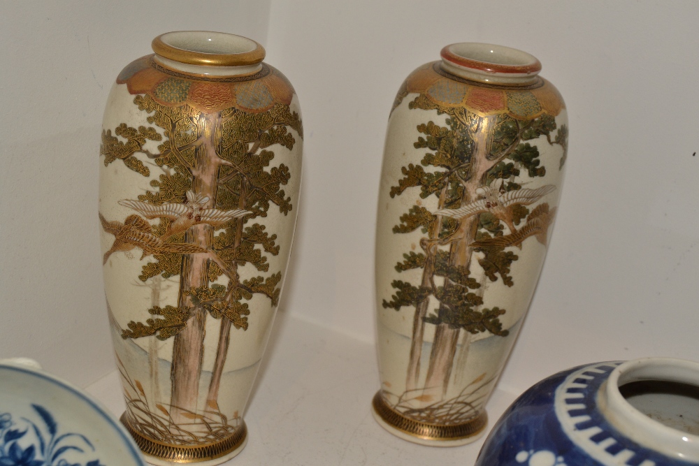 A pair of Japanese Satsuma slender ovoid vases, painted with cranes in flight, in colours,