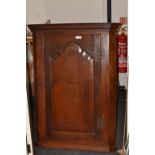 A George III oak splay fronted wall hanging corner cabinet, stepped cornice,