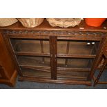 A mid 20h century oak glazed low bookcase, carved frieze, c.