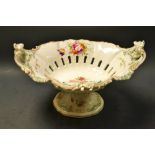 A continental porcelain pedestal oval dish, ornate flowering swag handles, painted floral swags,