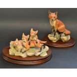 A Scottish Border Fine Arts model Fox Seated on Rocks,  another Trio of Fox Cubs at Play,