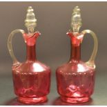 A pair of Victorian cranberry glass decanters, each with a single handle,
