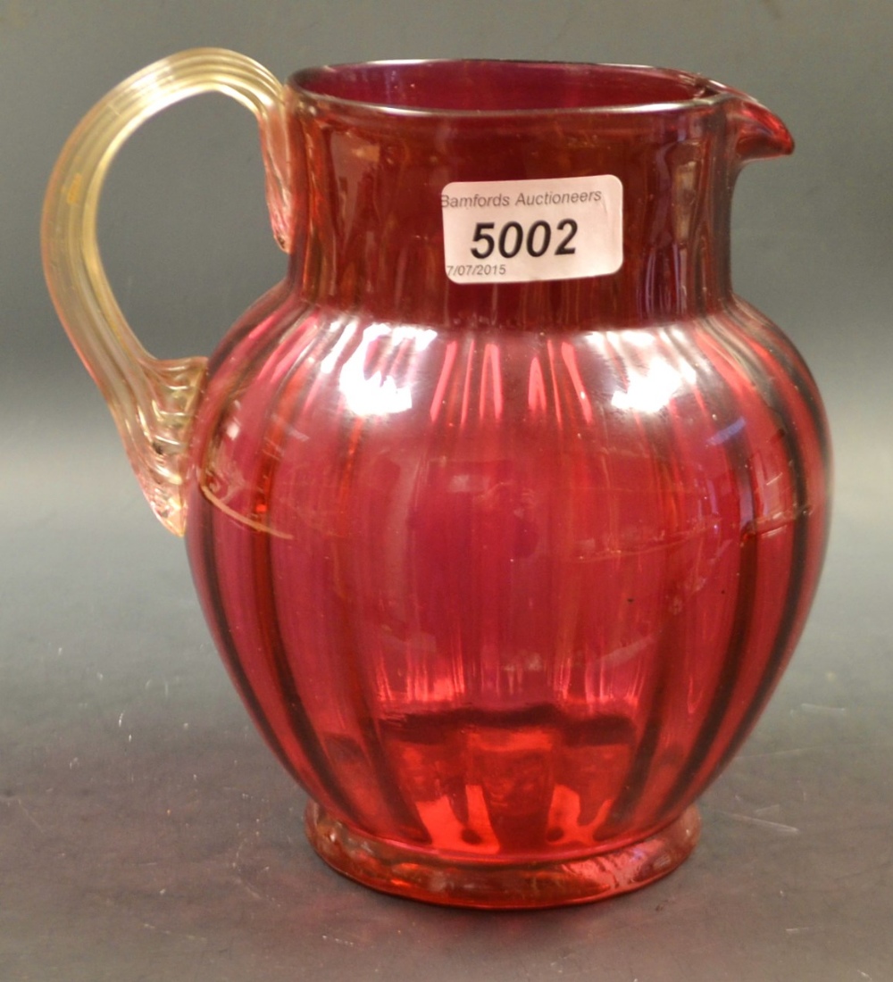 A Victorian cranberry glass ovoid water jug, clear glass reeded scroll handle, 19cm,