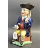 A Staffordshire Squire jug, seated on a corner chair, wearing a black tricorn hat,