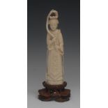 A Chinese ivory 'okimono', carved as an immortal, she stands, dressed in flowing robes,