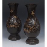 A pair of Japanese patinated bronze baluster vases, boldly cast with cranes and a choppy,
