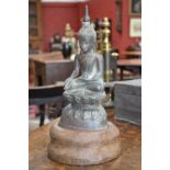 A Tibetan bronze Buddha, seated in dhyanasana, one palm open, the other holding an attribute,