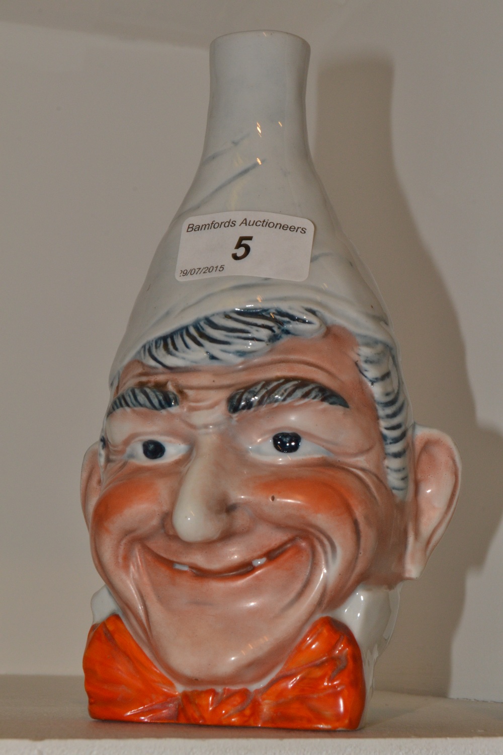 A Saxe Novelty mask vase, in relief with a comical man, wearing a red bow tie,