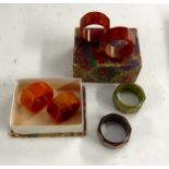 A set of six Bakelite napkin rings, of octagonal form, in hues of orange, green, brown and red,