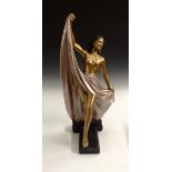 An Art Deco plaster model of a dancing woman, she holds her long skirt high in a dancing posture,