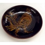 A Hawkshead terracotta slipware plate, applied with a grotesque bird, 25cm diam,