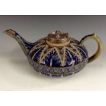 A Royal Doulton Lambeth compressed teapot, decorated in relief with blue and and green tones,