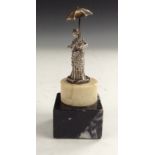 A white metal figurine of an Edwardian lady holding a parasol,