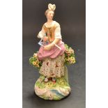 A Derby Patch figure, of a musician, she stands playing the triangle, wearing feathers in her hair,