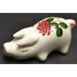 A Plicta pottery miniature model pig, paited with a single flower,