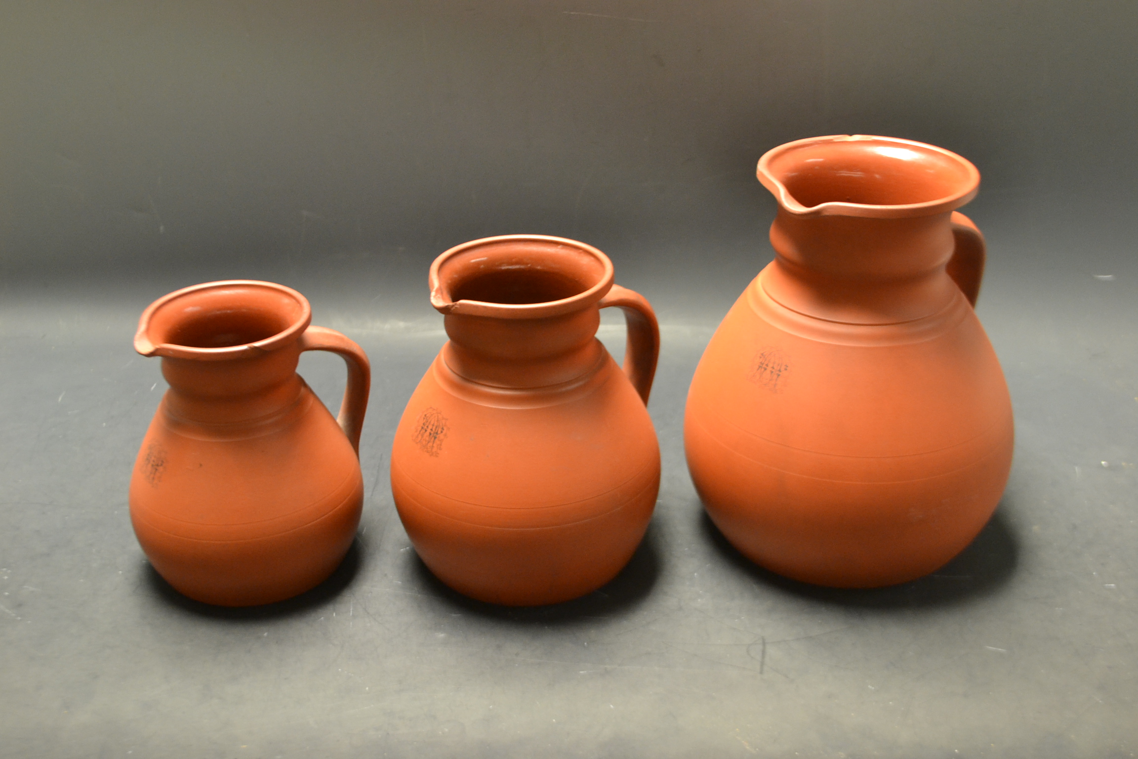 A graduated set of three Victorian Wedgwood terracotta globular ale jugs,