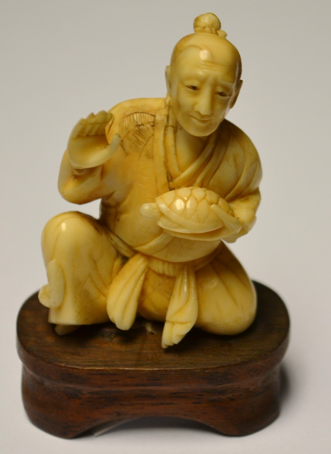A 19th century Japanese Okimono seated figure holding a tortoise