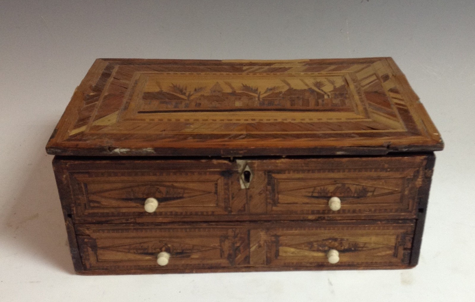 A Napoleonic prisoner of war straw work box, hinged cover decorated with buildings,