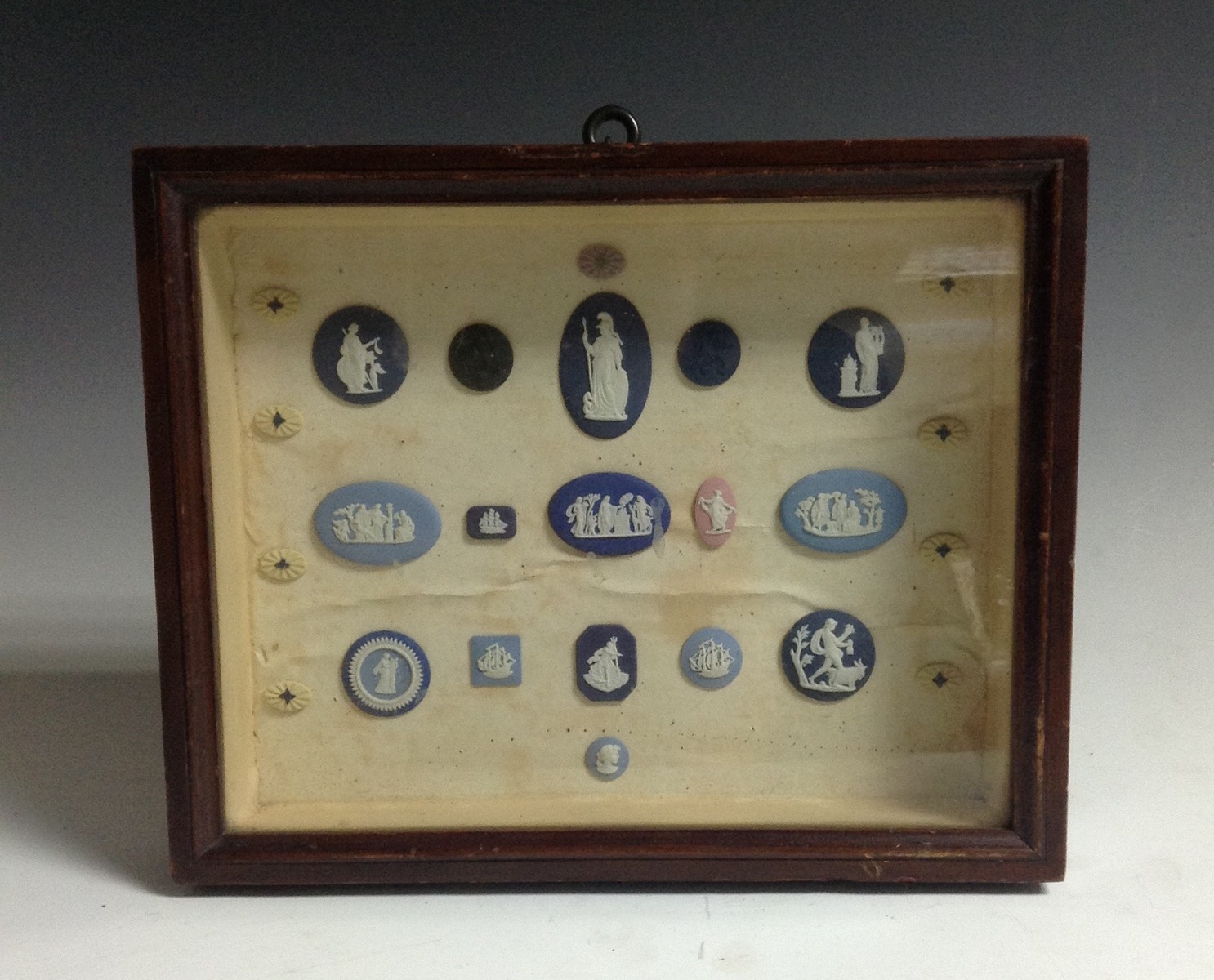 A collection of 19th century jasperware cameos, mounted in a display case, 20.5cm x 25.