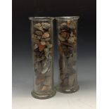 A pair of clear glass specimen cylinders, enclosing a collection of stones,