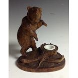 A Black Forest novelty inkwell, carved with a bear, on hind legs, traversing the woodland floor,
