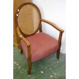 An early 20th century elbow chair, oval wickerwork back, open arms, stuffed overseat.