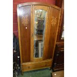 An early 20th century oak wardrobe, central arched mirrored door, flanked by carved panels,