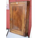 A mahogany wall mounted corner cupboard, canted angles, panel door enclosing shelving.