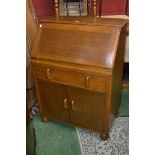 A 1950's oak bureau, fall front over long drawer and two door cupboard.