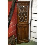 An oak floor standing corner cabinet, glazed leaded light to top,