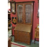 A George III oak bureau book case, the top with glazed doors, the projecting base with fall front,