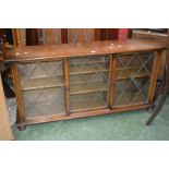 A mahogany low bookcase with three lead glazed sliding doors.