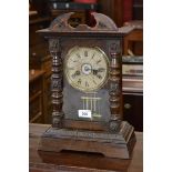 A stained pine mantel clock, outswept cornice, Roman numerals.