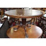 A mahogany loo table, oval top, tapering octagonal column, three cabriole legs, lion paw feet,