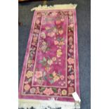 A woolwork rug, woven with flowers on a magenta ground,