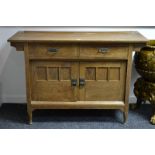 A Liberty and Co oak dresser base, the oversailing top above two short drawers, two panelled doors,