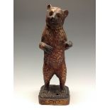 A Bretby model of a grizzly bear, he stand erect with outstretched paws wearing a collar,